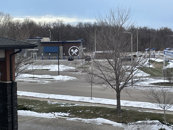 Daytime view from hotel window showing Culver's restaurant with distinctive spoon and fork logo, snow on ground, parking lot and bare trees