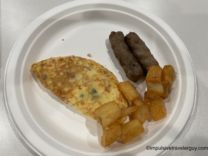 White plate containing Western omelet with diced potatoes and two breakfast sausage links