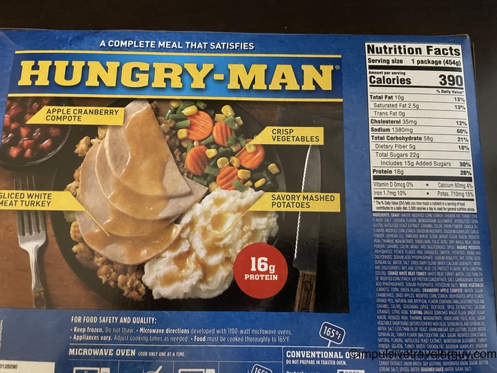 Back of a Hungry-Man frozen dinner box for roasted turkey meal, showing sliced white meat turkey with gravy, stuffing, mashed potatoes, apple cranberry compote, and mixed vegetables. Nutrition facts show 390 calories and 16g protein.