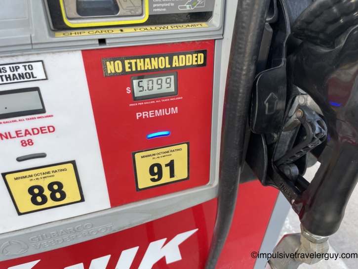 Close-up of the Kwik Trip pump face showing 91-octane premium selected at $5.099 per gallon with a 'No Ethanol Added' label, the blue selection indicator lit, and the nozzle inserted in the car.