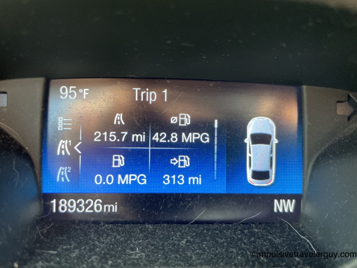 Car dashboard trip computer showing 189,326 total miles, 95 degrees outside, 215.7 miles on the trip at 42.8 MPG with 313 miles of range heading northwest.