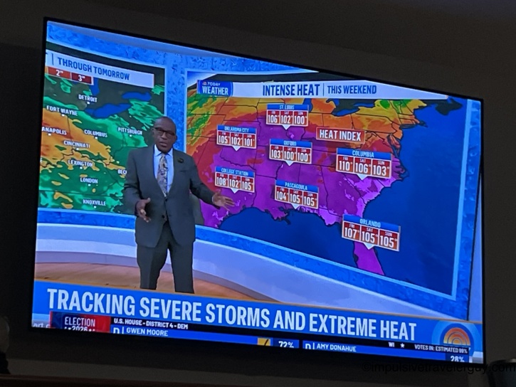 Television screen displaying a weather broadcast about intense heat and severe storms, featuring a meteorologist standing in front of a heat index map of the southern and midwestern United States showing College Station at 108 degrees.