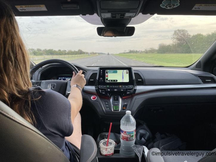 View from the back seat of the van showing Victoria driving on a highway heading north.