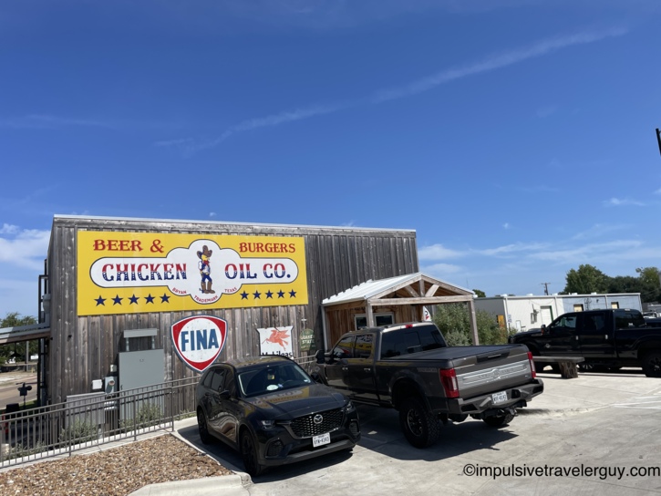 Exterior view of the rustic Chicken Oil Co. restaurant building featuring weathered wood siding and bright yellow signage.