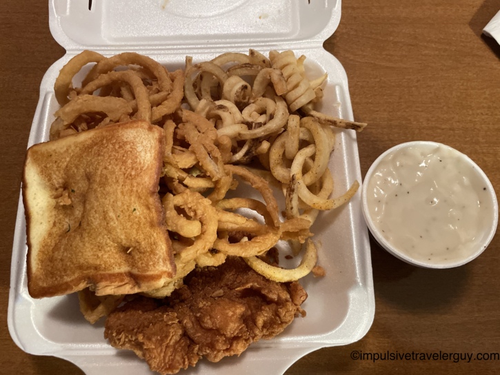 A takeout container from Wings 'N More filled with chicken fried chicken, curly fries, a slice of Texas toast, and a side cup of white gravy.