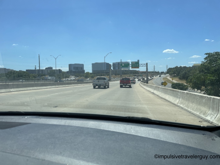 Driving view approaching The Domain in Austin, showing its newly developed business district skyline featuring several modern office buildings.