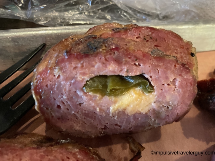 Close-up of a sliced Sausage Slammer revealing a center stuffed with a jalapeño pepper and melted cheese.