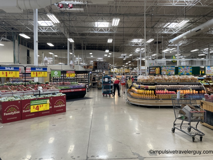Brightly lit interior of the expansive H-E-B grocery store showing wide aisles and a fresh produce section.