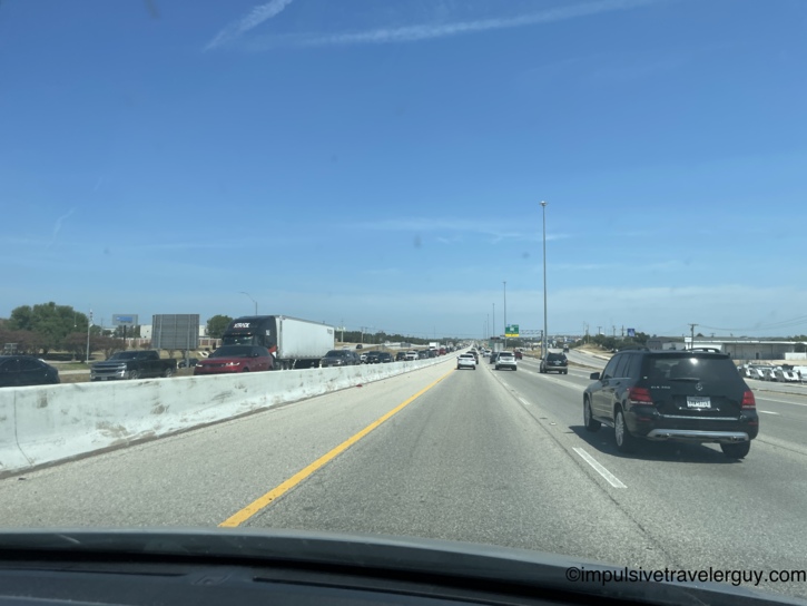 View from a vehicle leaving Austin, looking at heavy traffic entering the city on the opposite side of the highway.